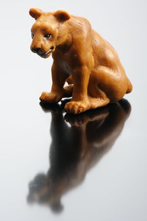 A plastic figurine of a lioness and its reflection on a black backgroundの写真素材