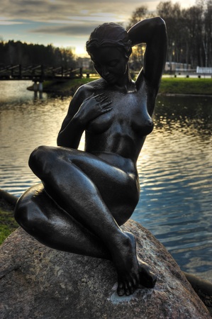 Bronze sculpture of a girl on a rock in a city parkの写真素材