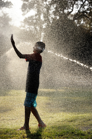 Children play with jets of water in hot weatherの写真素材