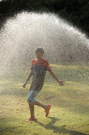 Children play with jets of water in hot weatherの写真素材
