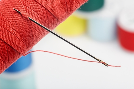 Spool with thread and needle on white background