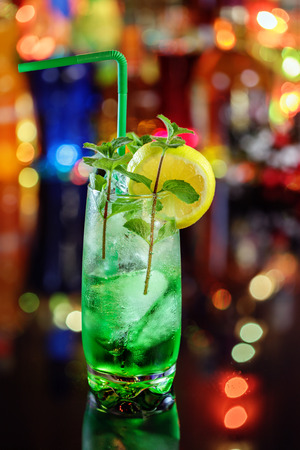 Cocktail with mint and lemon on the bar on the blur background.の写真素材