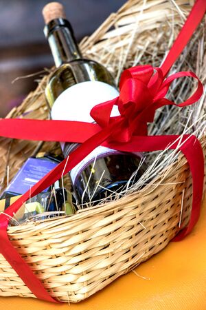 A bottle of wine in a beautiful basket with a red ribbon, a beautiful postcardの写真素材