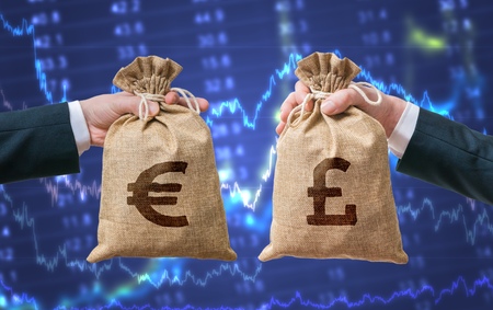 Currency exchange concept. Hands holds bags full of money - British pounds and Euro.の写真素材