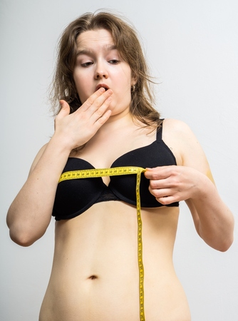 Young woman is shocked after measuring her breast size.の写真素材