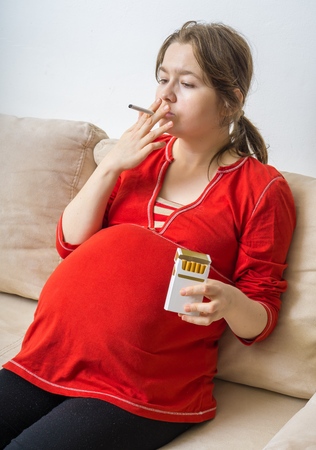 Smoking in pregnancy. Pregnant woman holds cigarette in hand.の写真素材