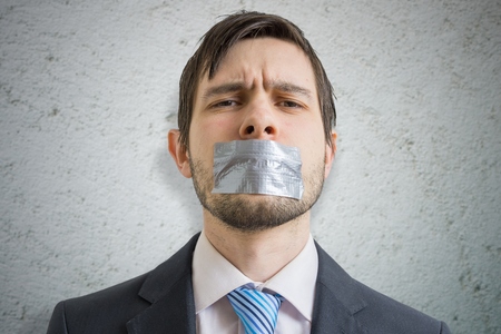 Censorship concept. Young man is silenced with duct tape over his mouth.