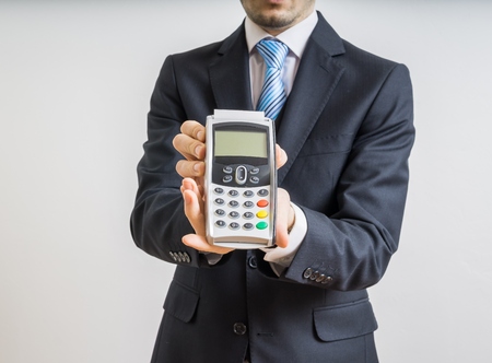 Payment with credit card. Businessman holds payment terminal in hand.の写真素材