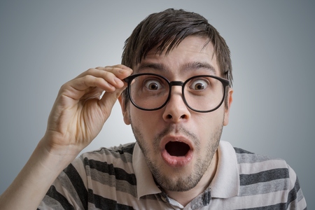 Nerdy man has open mouth and is surprised and shocked.