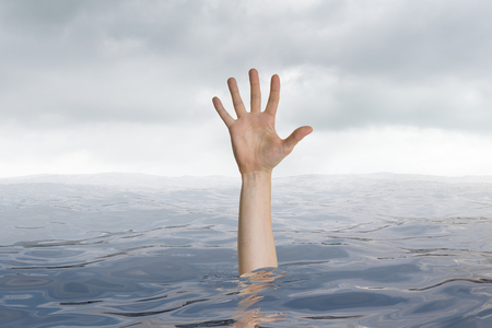 Man is drowning in ocean. Only hand is visible.の写真素材