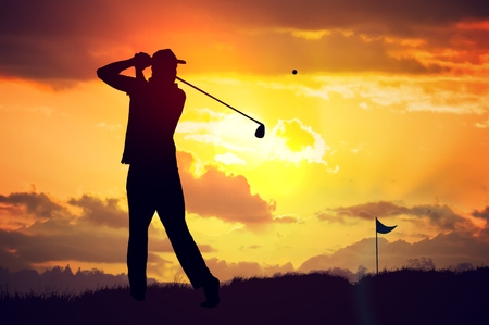 Silhouette of man playing golf at sunset.の写真素材