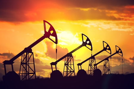 Many silhouettes of drilling oil rigs at sunset.の写真素材