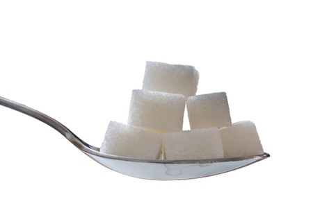Close up view on spoon with many sugar cubes. Isolated on white background.の写真素材