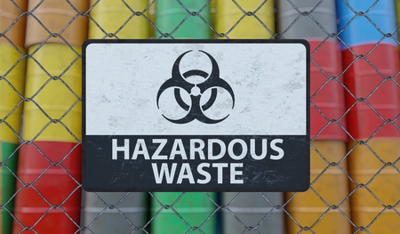 Hazardous waste sign on chain link fence. Oil barrels in background. 3D rendered illustration.の写真素材