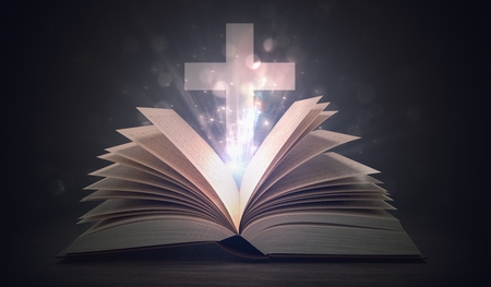 Christianity concept. Open shining holy bible and cross above.の写真素材
