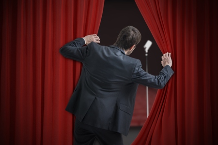 Nervous man is afraid of public speech and is hiding behind curtain.の写真素材
