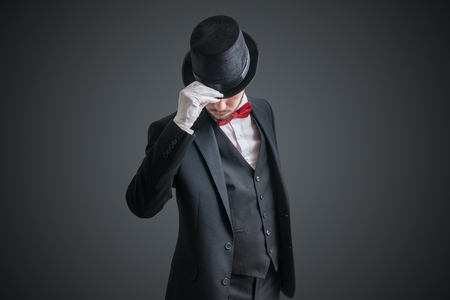 Gallant magician or illusionist in suit is taking off his hat.の写真素材