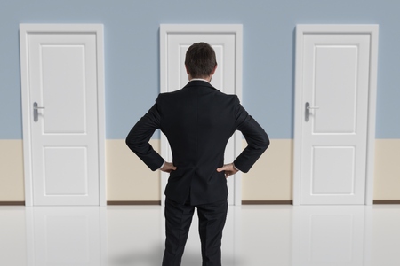 Businessman from behind is making decision and selecting the door.の写真素材