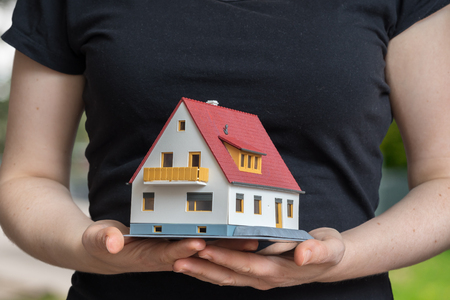 Real estate agent is holding small house in hand.の写真素材