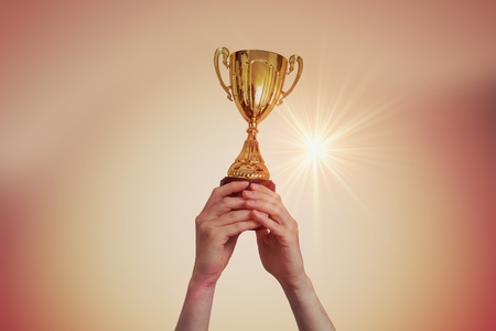 Winner is raised up a trophy in sunset.