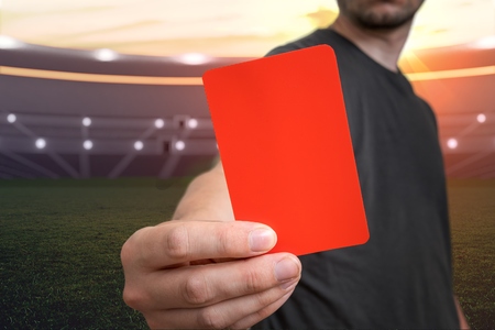 Referee is showing red card as a penalty for a foul in soccer stadium.の写真素材
