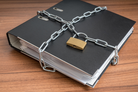 Confidential files and documents in binder locked with padlock and chain. Privacy and security concept.の写真素材