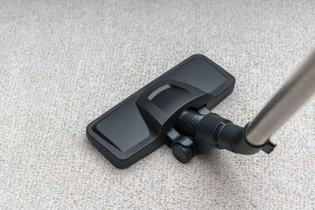 Vacuum cleaner is cleaning dust from carpet. Housework cocnept.