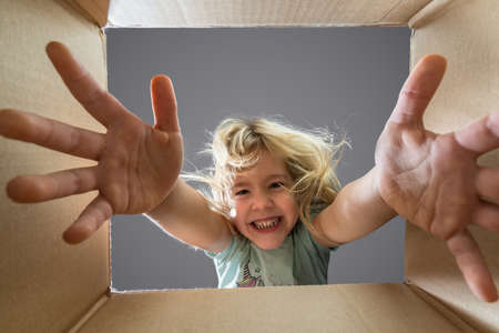 Happy child girl is opening a gift and looking inside cardboard box.の写真素材