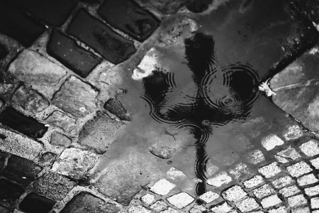 Rain and city light mirrors in the puddleの写真素材