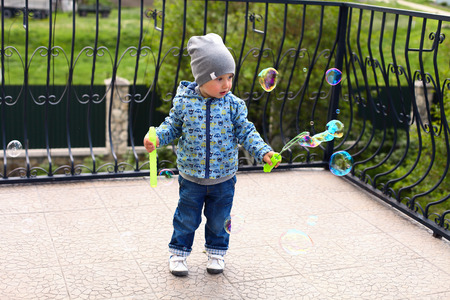child playing with big colorful  soap bubbles