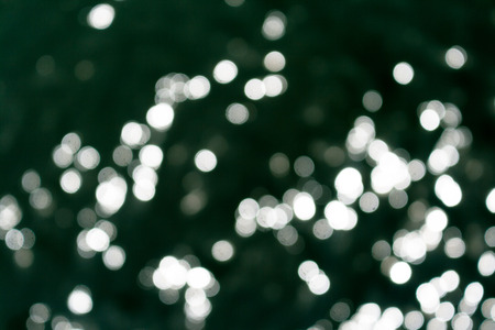 Sun lights bokeh white on sea surface in black backgroundの写真素材