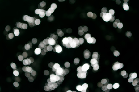 Sun lights bokeh white on sea surface in black backgroundの写真素材