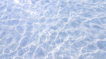 blue water wave with shining white twinkling from the sun backgroundの写真素材