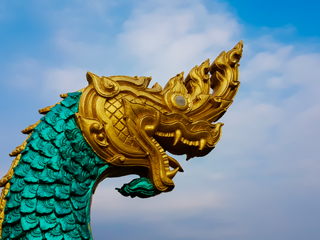 statue of a large serpent in golden head and green body with blue sky  backgroundの写真素材