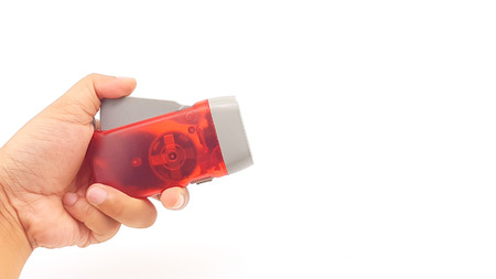 Hand pressing LED flashlight red plastic holder with hand rope isolatedの写真素材