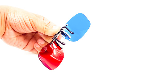 Man hand holding plastic clip of blue and red three dimensional glasses isolatedの写真素材