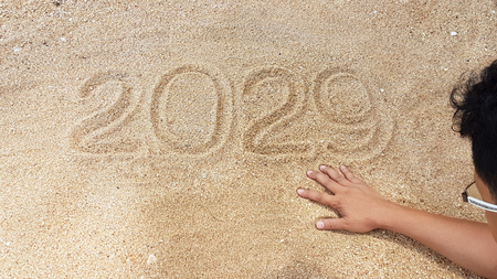 The Year handwriting on golden sand with survivor of man's hand view