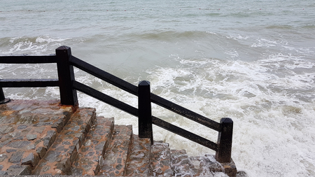 Ocean wave hits the shore with a stone stair on the bankの写真素材