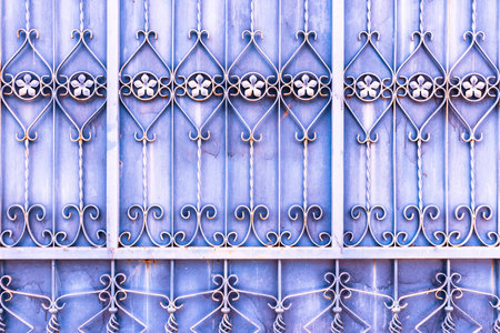 Rusty purple metal door with knit flower pattern and metal spiral background