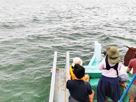 Tourist on travel ship who was waiting for photograph something in the sea with strong waves with cloudy white sky background.の写真素材
