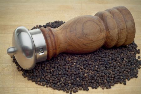 Pepper Mill in pepper on wooden cutting board horizontalの写真素材