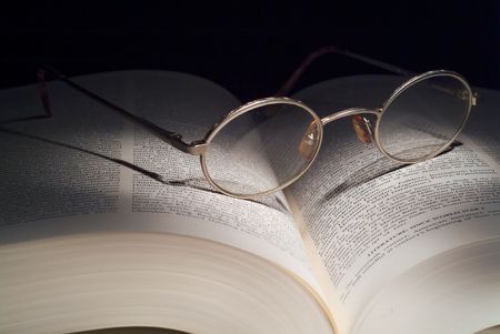 Reading glasses on large book. Lighting is painting with light.