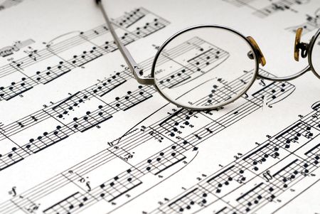 Old reading glasses resting on old sheet musicの写真素材