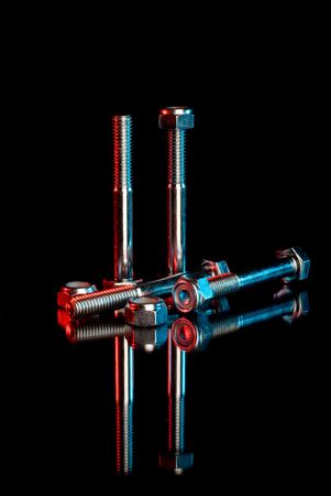 Industrial looking nuts and bolts on a reflective surfaceの写真素材