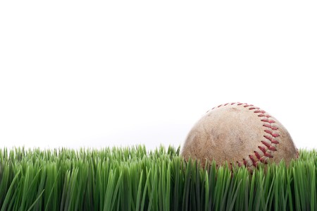 A worn leather baseball in grass with a white backgroundの写真素材