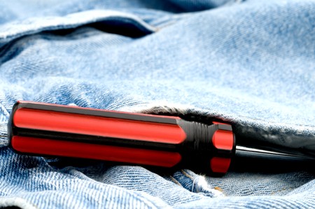 Red and black screwdriver in jeans pocketの写真素材