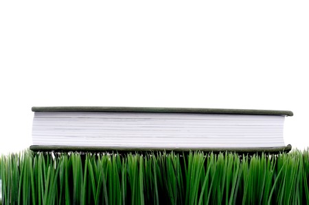 Green hardcover book sitting on grass with a white backgroundの写真素材