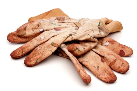 Horizontal view of old worn work gloves on reflective white surfaceの写真素材