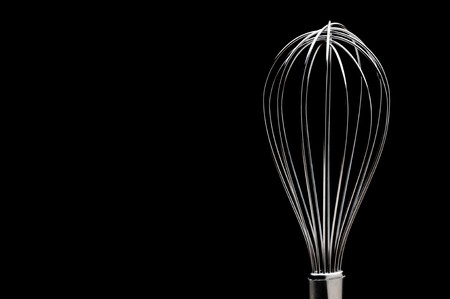 A silver stainless steel whisk on a black backgroundの写真素材