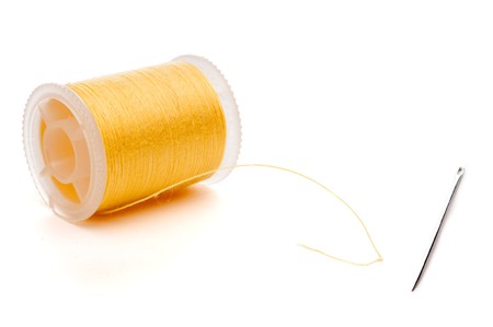 Horizontal extreme closeup of a yellow spool of thread and a needleの写真素材